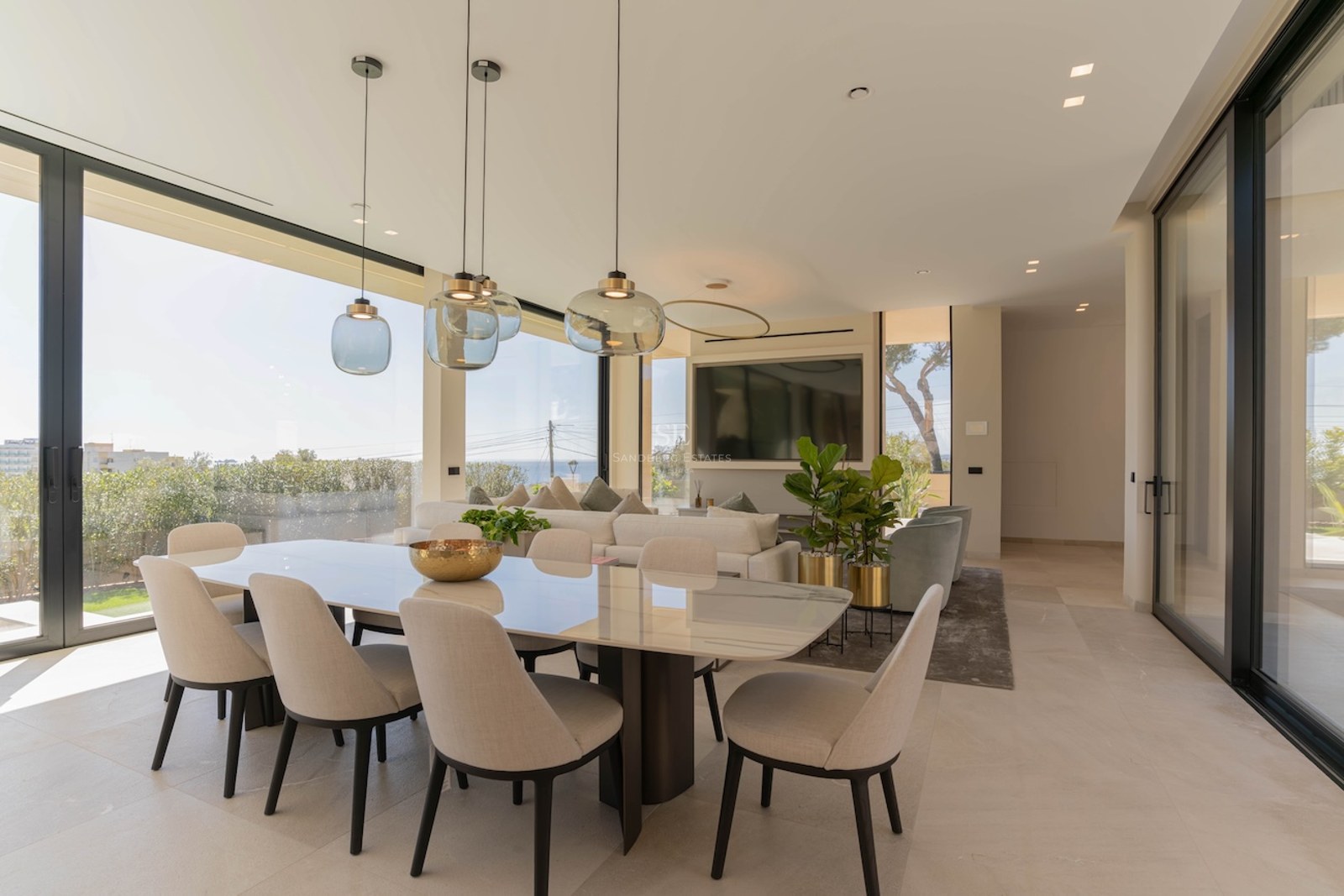 Salle à manger moderne avec table en marbre et baies vitrées offrant une vue imprenable sur la mer.