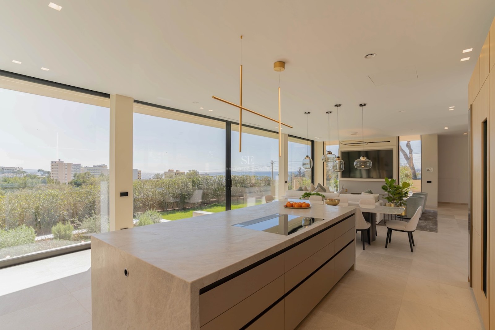 Cuisine contemporaine avec îlot en pierre, meubles en chêne et baies vitrées offrant une vue sur le jardin.