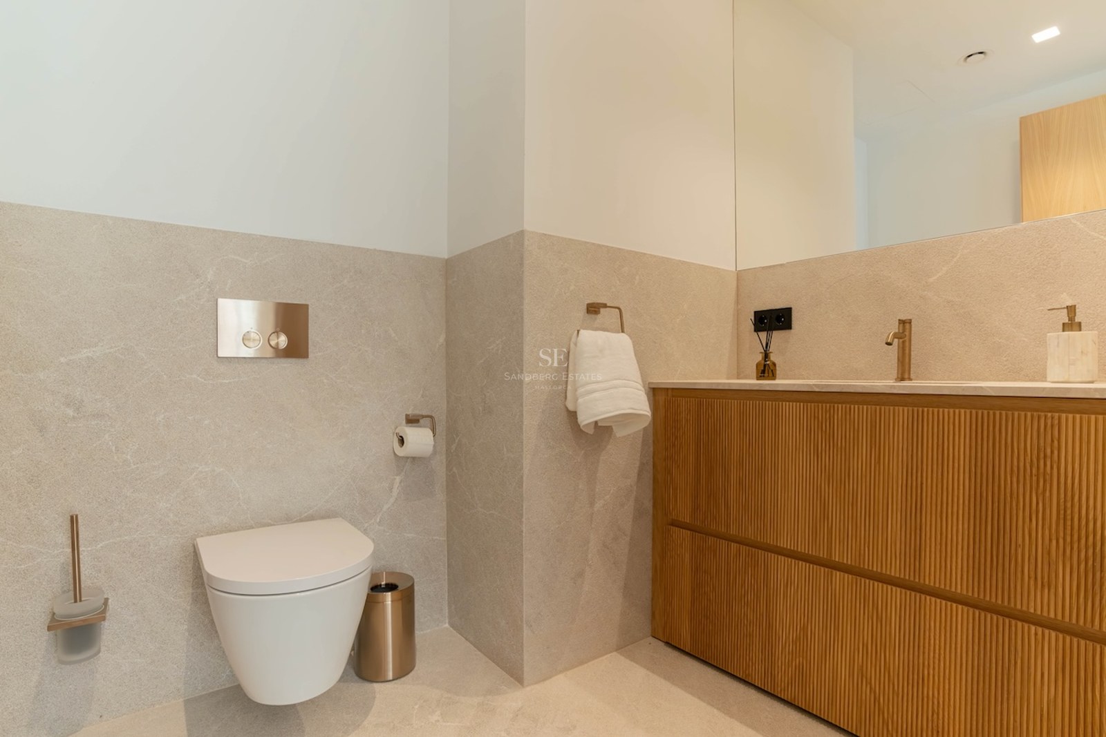 Salle de bains contemporaine avec toilettes suspendues, meuble vasque en chêne et murs en pierre beige.