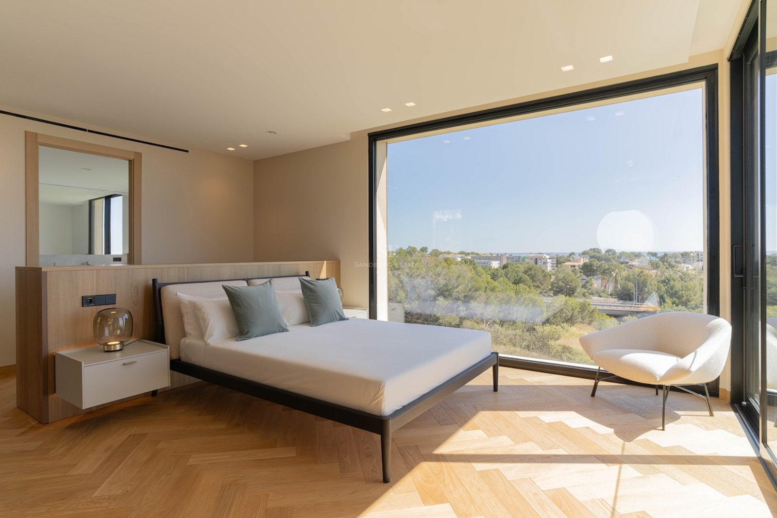 Chambre contemporaine avec parquet en chêne en point de Hongrie et grande baie vitrée donnant sur un paysage verdoyant.