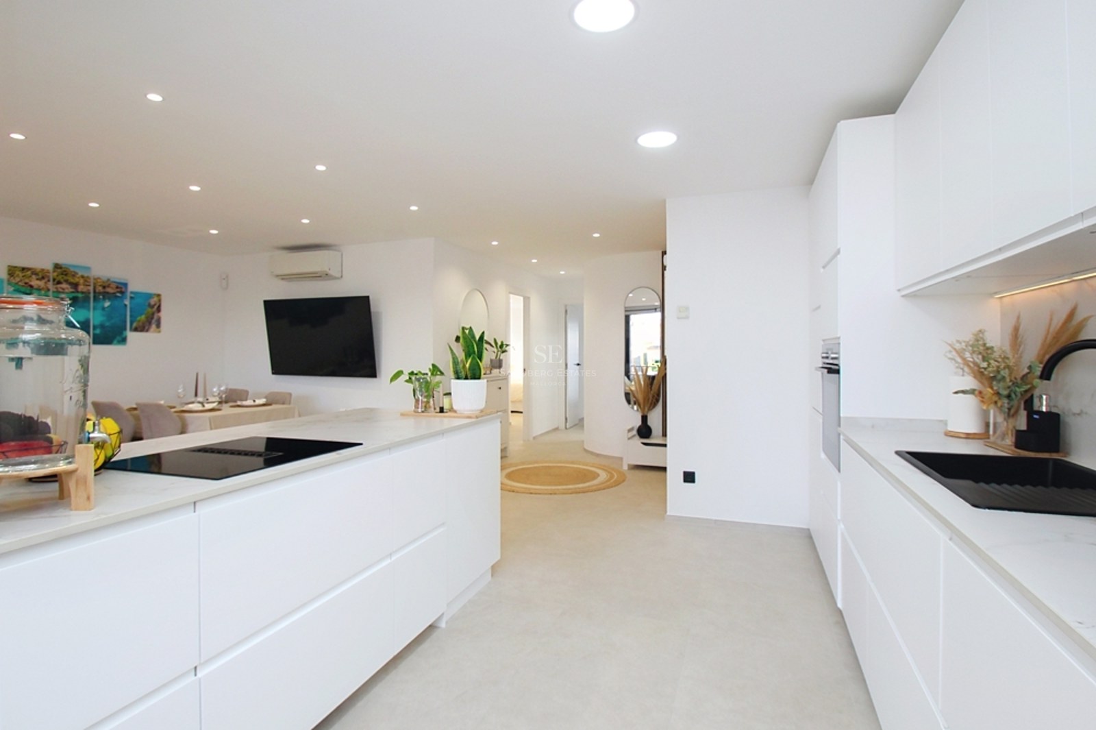Cocina contemporánea en color blanco brillante con isla central, fregadero negro e iluminación empotrada.