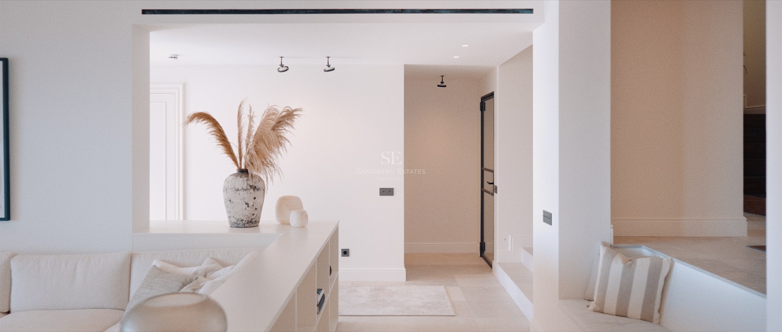 Sunken living area with off-white sofa, decorative pampas grass in a stone vase, and clean white walls.