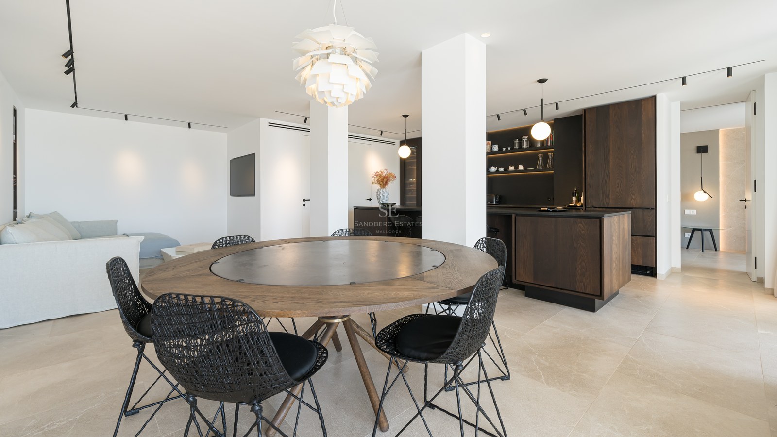 Table à manger ronde en bois avec chaises tressées noires dans un espace de vie moderne ouvert.