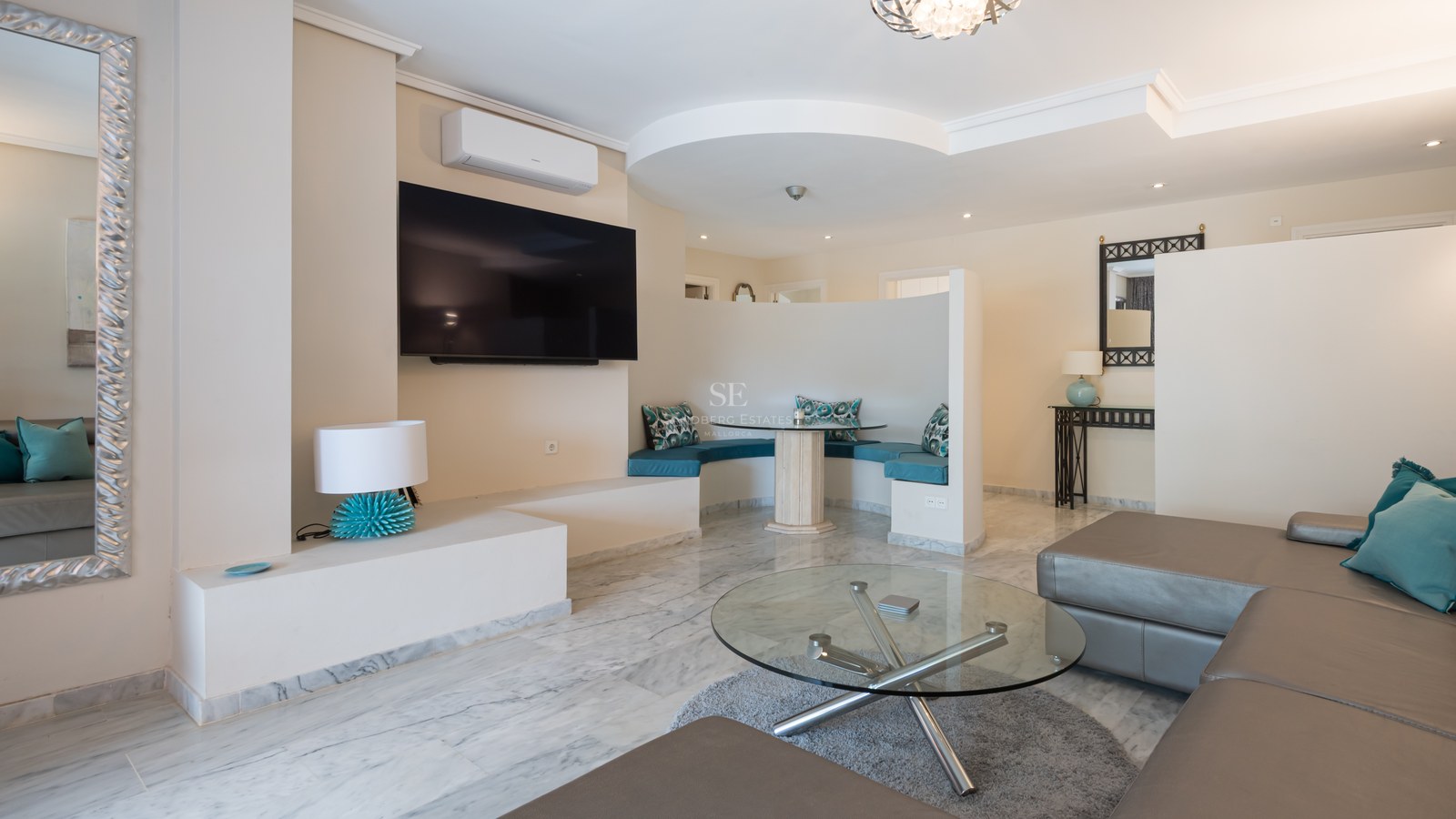 Salon moderne avec sol en marbre, canapé en cuir et un coin petit-déjeuner incurvé avec coussins turquoise.
