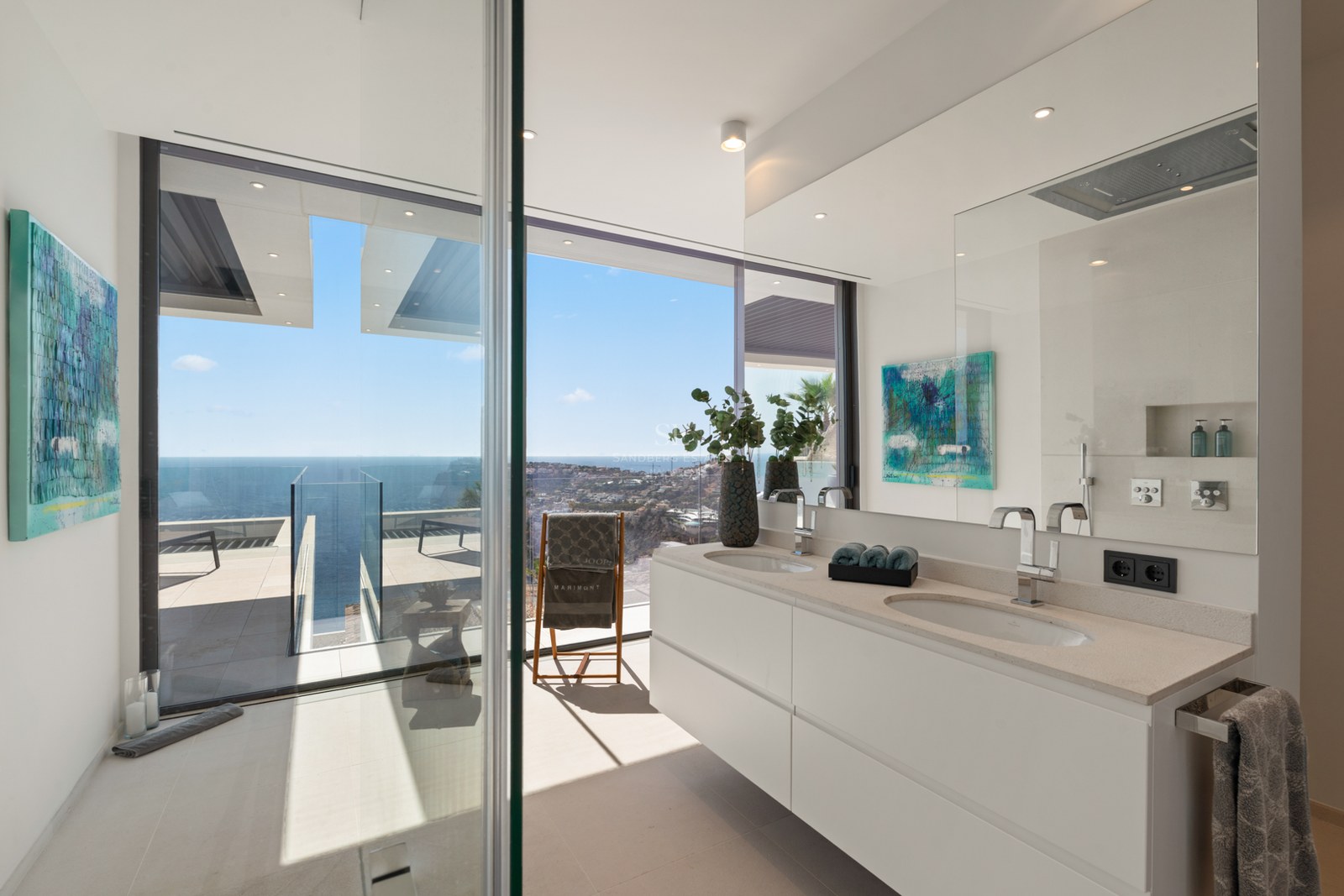Salle de bain moderne avec double vasque blanche et grandes baies vitrées offrant une vue sur la Méditerranée.