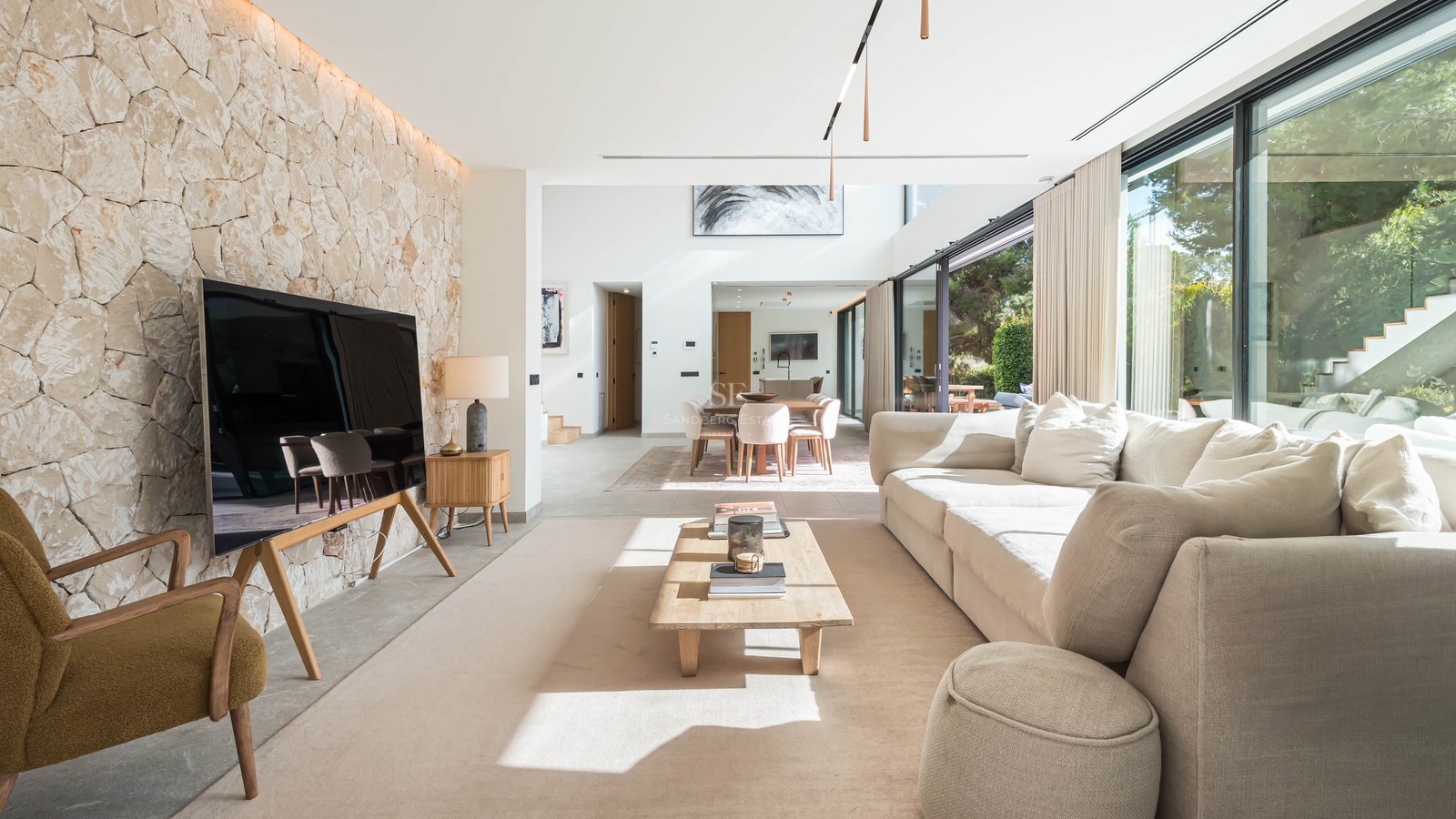 Salon spacieux avec un grand canapé crème, une table basse en bois et un mur d'accent en pierre naturelle claire.