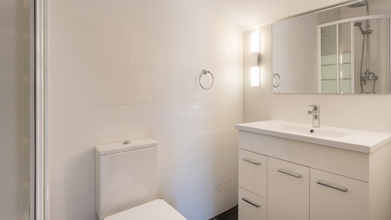 Salle de bain moderne avec carrelage blanc, meuble sous-vasque à tiroirs et robinetterie chromée.