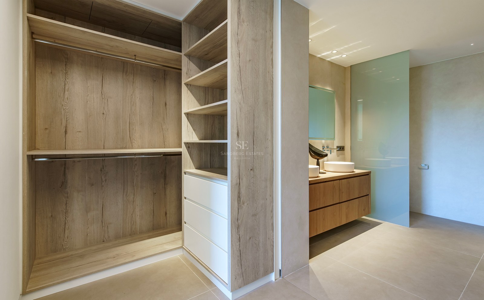 Dressing moderne avec menuiserie en chêne menant à une salle de bains avec double vasque et paroi en verre dépoli.