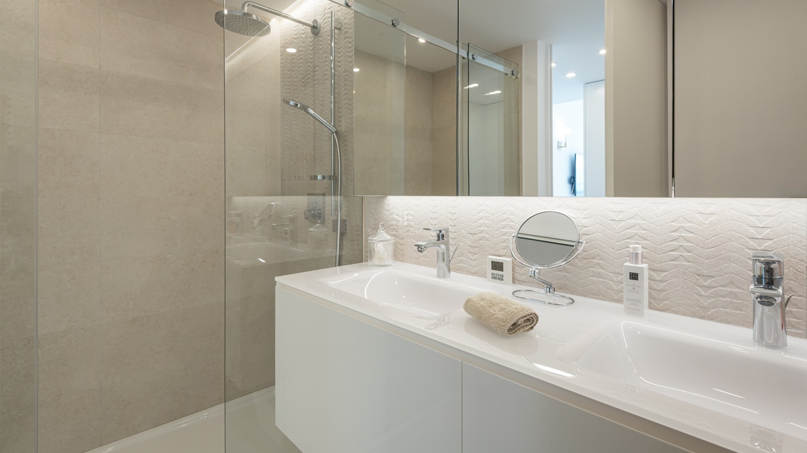 Modern bathroom featuring a white double vanity, glass-enclosed shower, and textured beige tile backsplash.