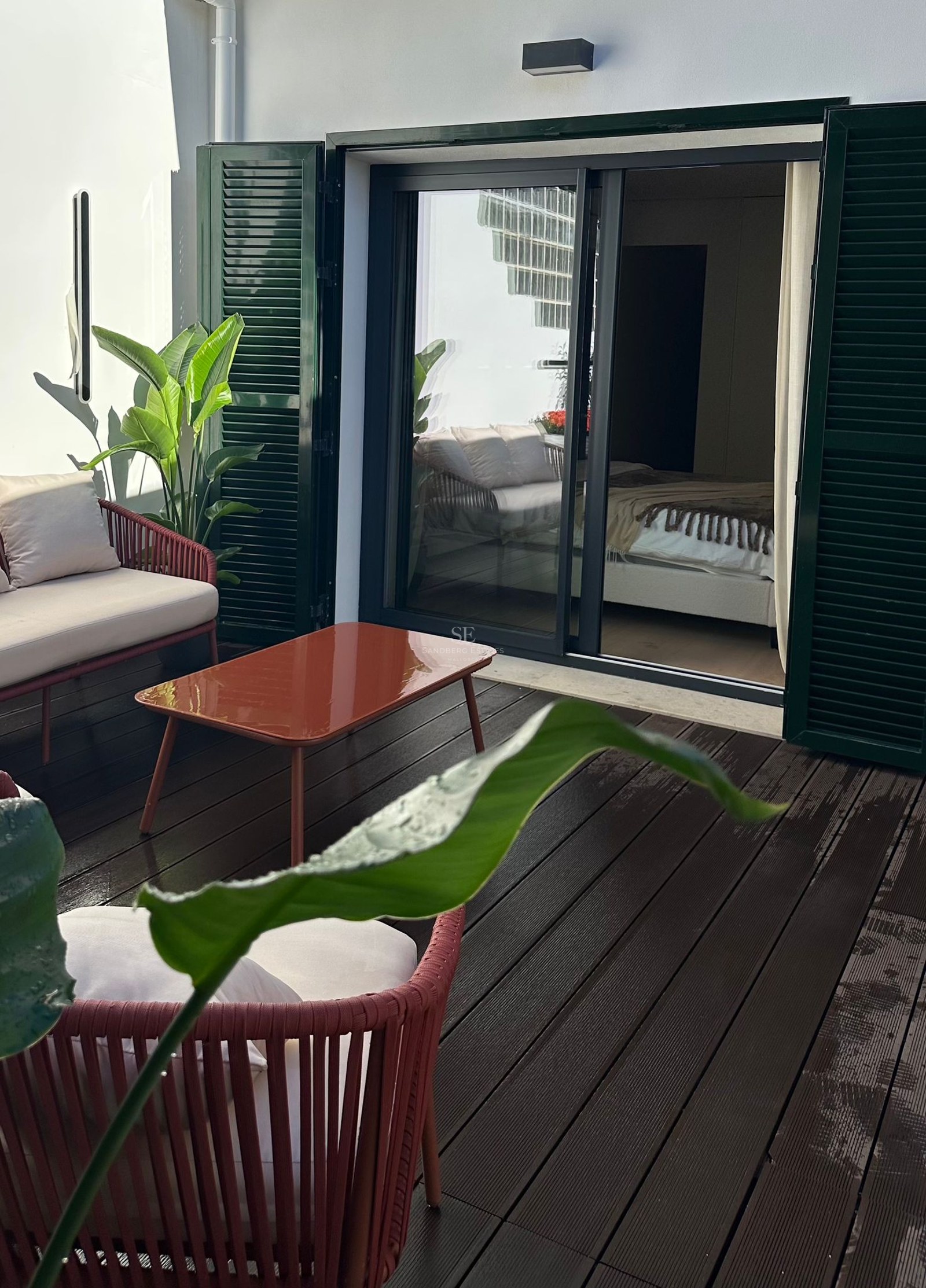 Terrasse privée avec mobilier terre cuite, plancher en bois et volets verts près de l'entrée de la chambre.