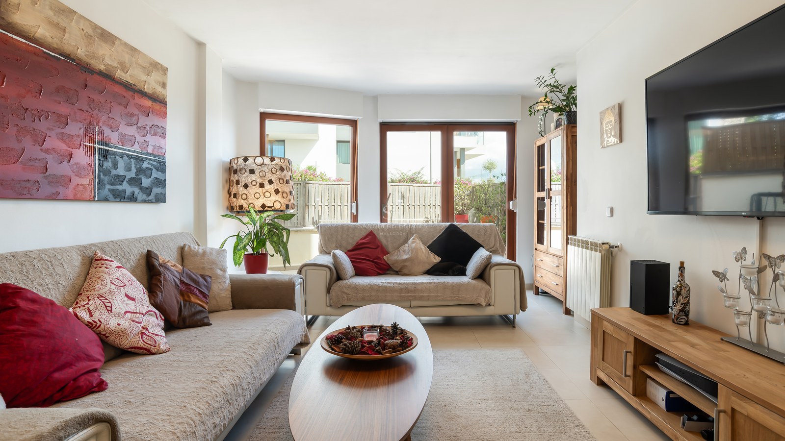 Salón iluminado con sofás beige, muebles de madera y grandes puertas de cristal que dan a una terraza privada.