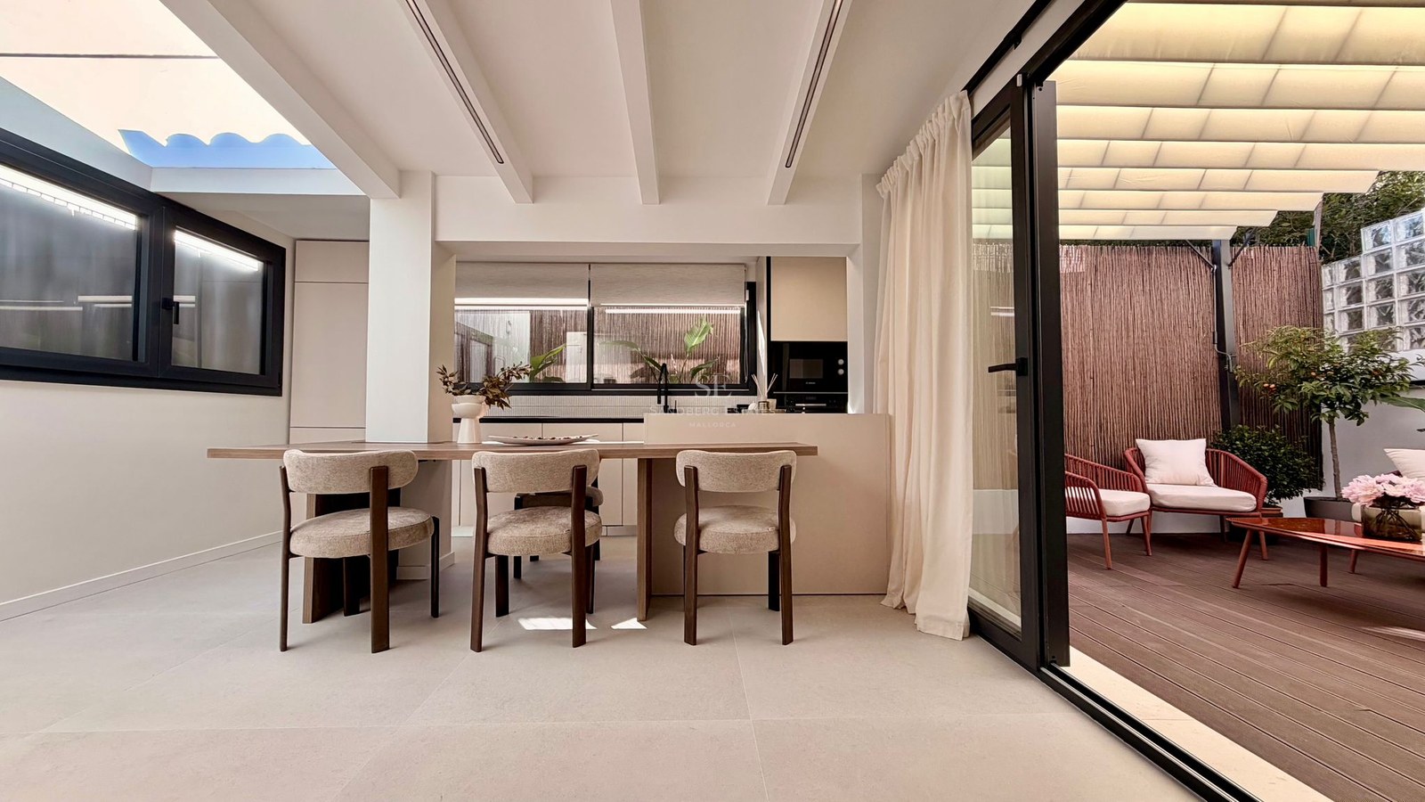 Salle à manger moderne avec table en bois et chaises design à côté d'une baie vitrée ouvrant sur une terrasse privée.