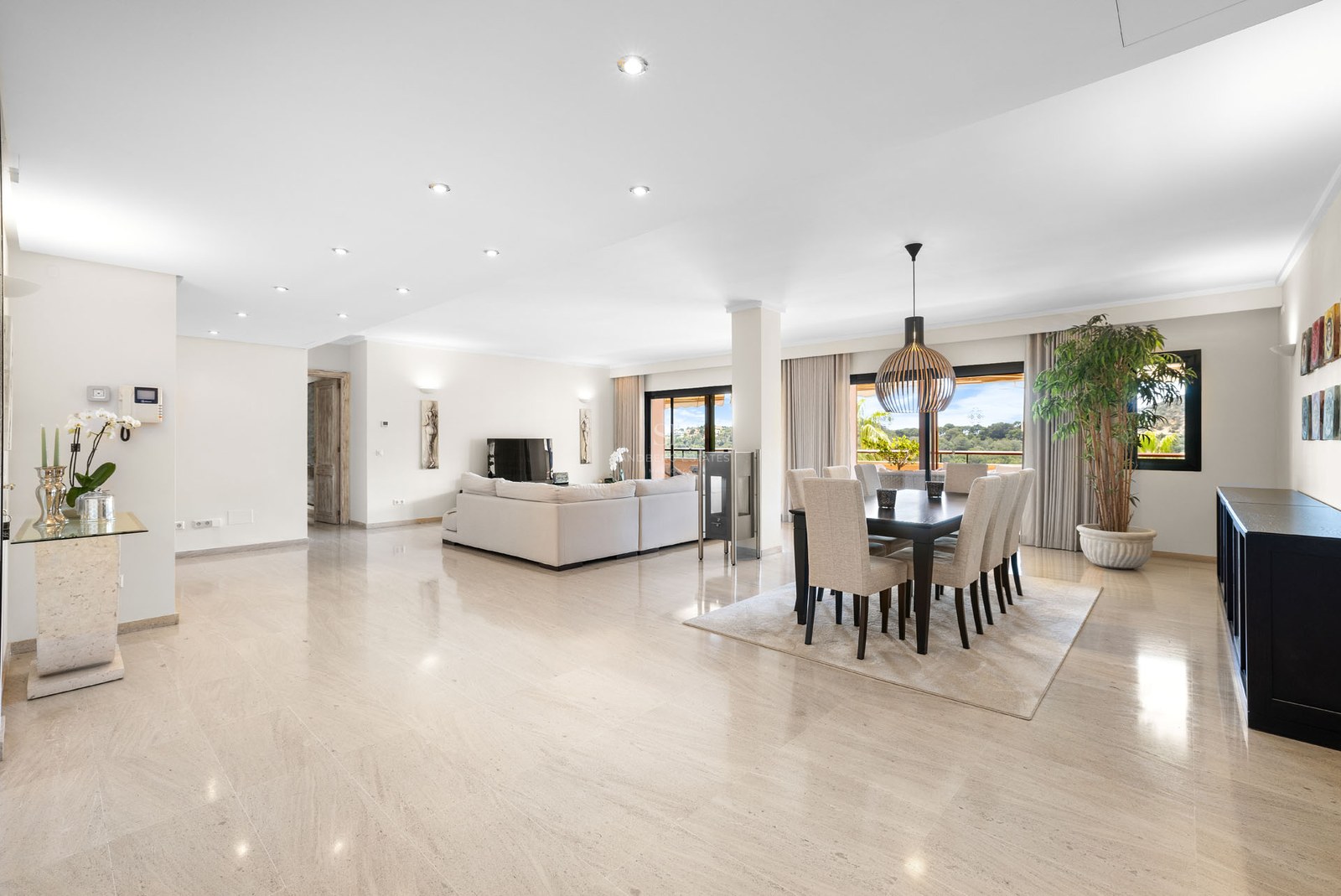 Intérieur lumineux à aire ouverte avec sols en marbre poli, un grand canapé blanc et une salle à manger moderne.