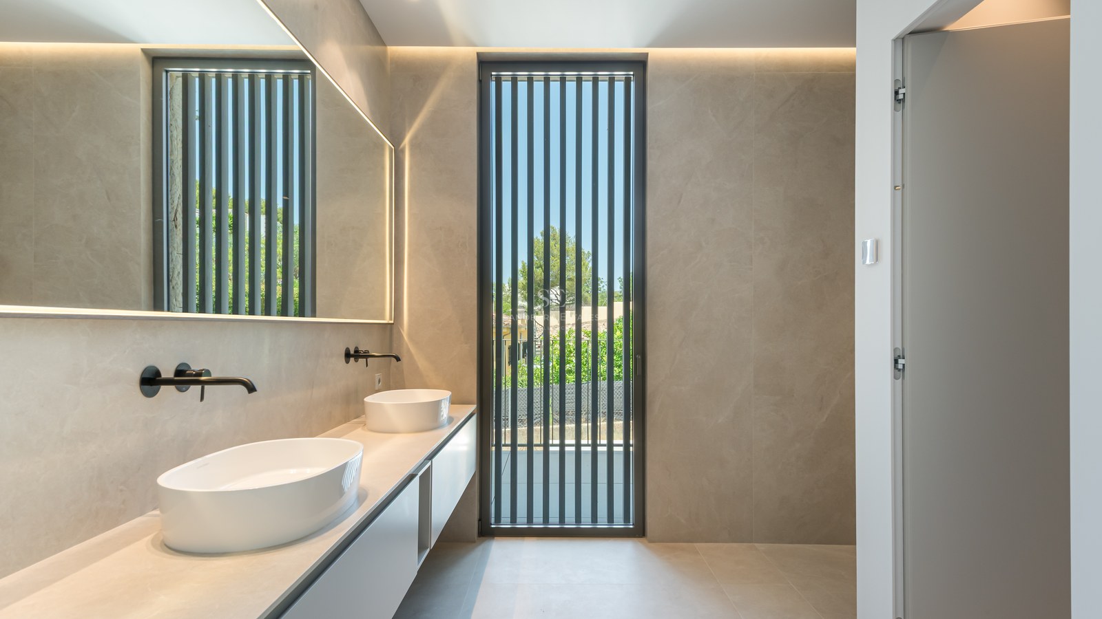 Salle de bain moderne avec double vasque ovale, robinetterie noir mat et grand miroir rétroéclairé.
