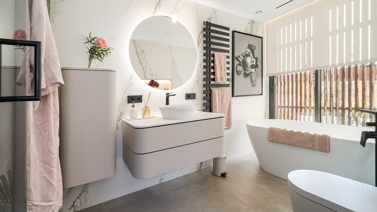 Salle de bain moderne avec miroir rond rétroéclairé, meuble suspendu et baignoire îlot blanche.
