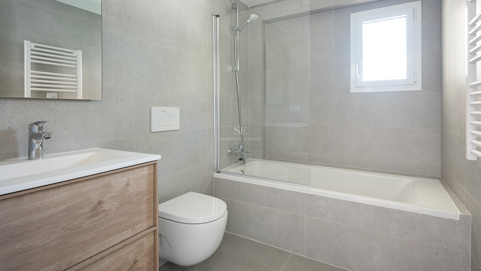 Salle de bain contemporaine avec carrelage gris effet pierre, baignoire et paroi en verre, et meuble sous vasque en chêne.