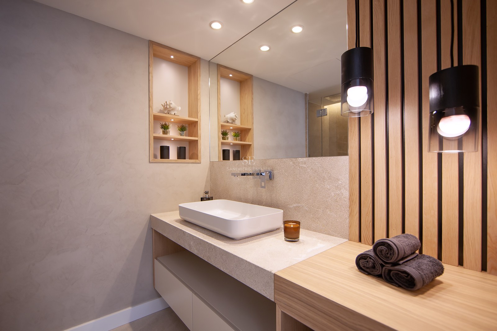 Modern bathroom featuring a white vessel sink, stone countertop, wooden slat wall, and warm pendant lighting.