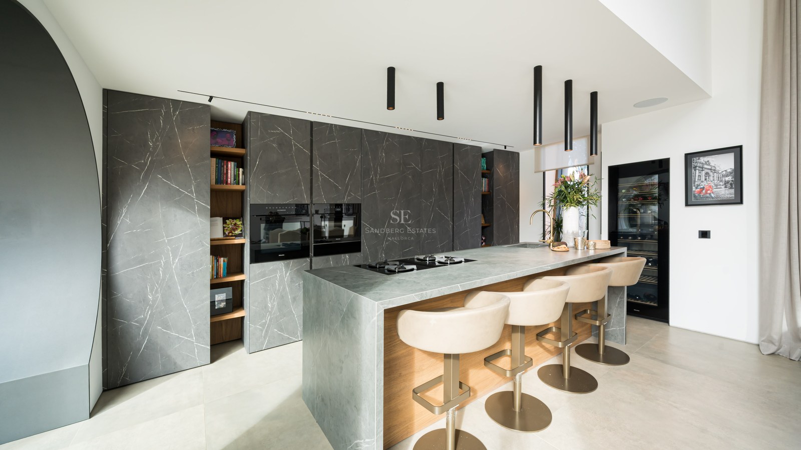 Cuisine moderne, placards marbre anthracite, îlot en pierre grise avec bar et suspensions design noires.