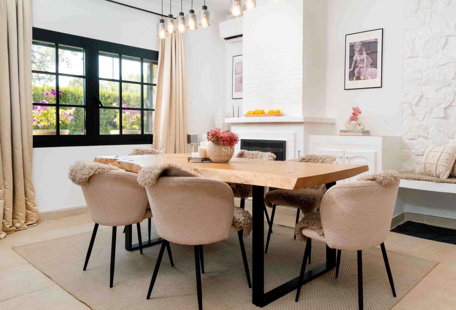 Modern dining room featuring a live-edge wooden table, beige bouclé chairs, and a white fireplace.
