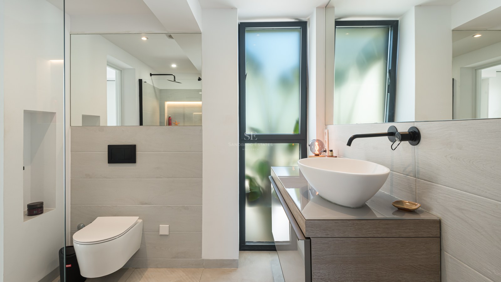 Contemporary bathroom featuring a white vessel sink, matte black faucet, wall-mounted toilet, and large mirrors.