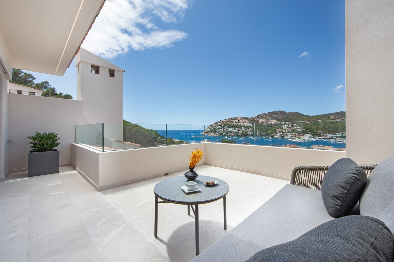 Luxury terrace with glass railings, outdoor sofa, and a breathtaking view of a Mediterranean harbor.