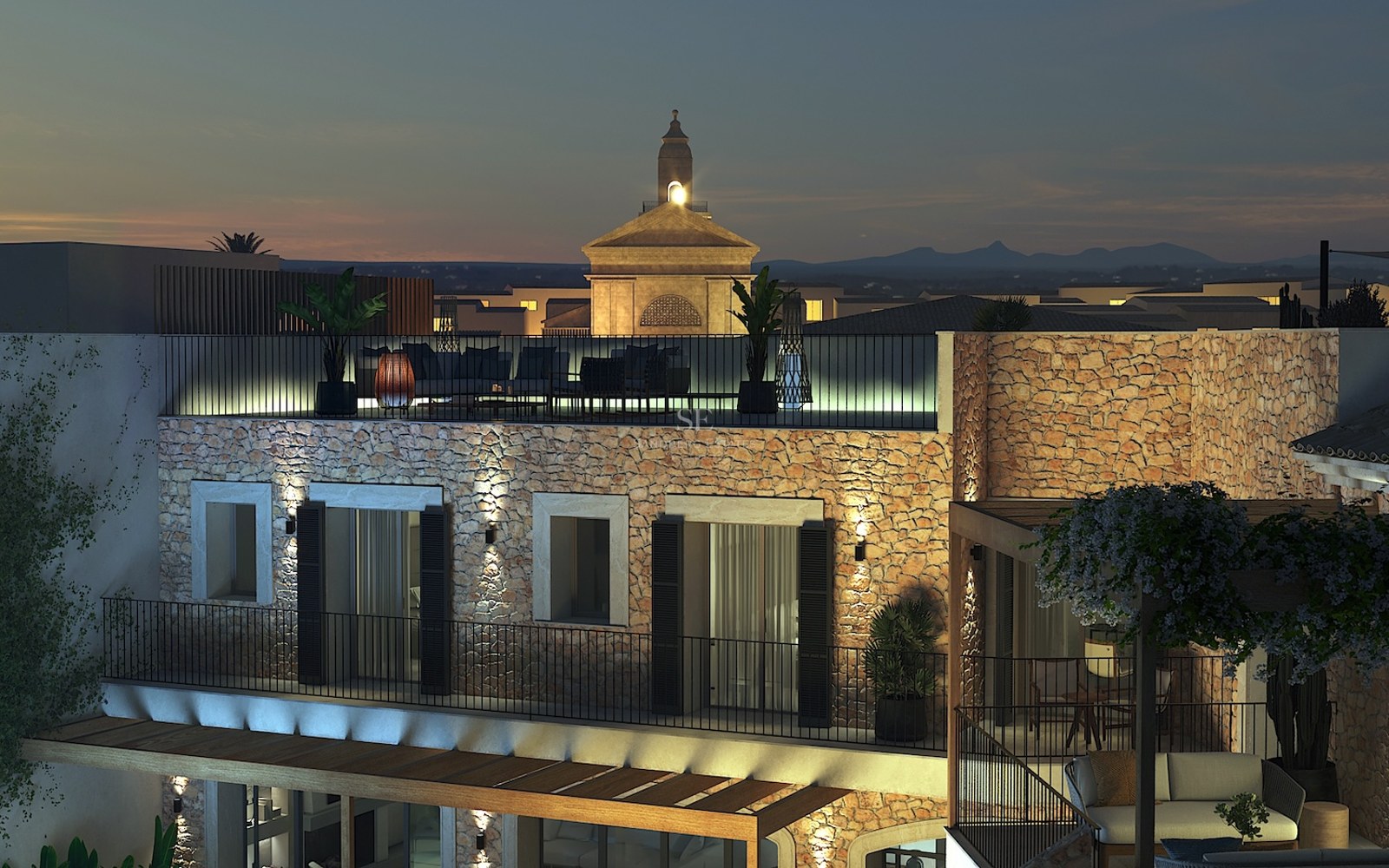 Vue nocturne d'une villa méditerranéenne avec murs en pierre éclairés et terrasse de toit dominant le village.