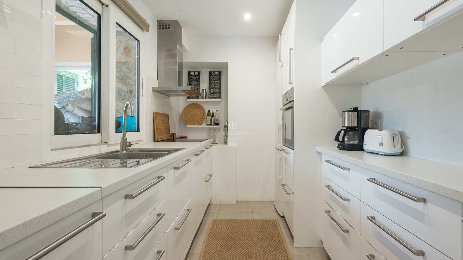 Cuisine lumineuse avec placards blancs brillants, plans de travail en quartz et appareils en inox.
