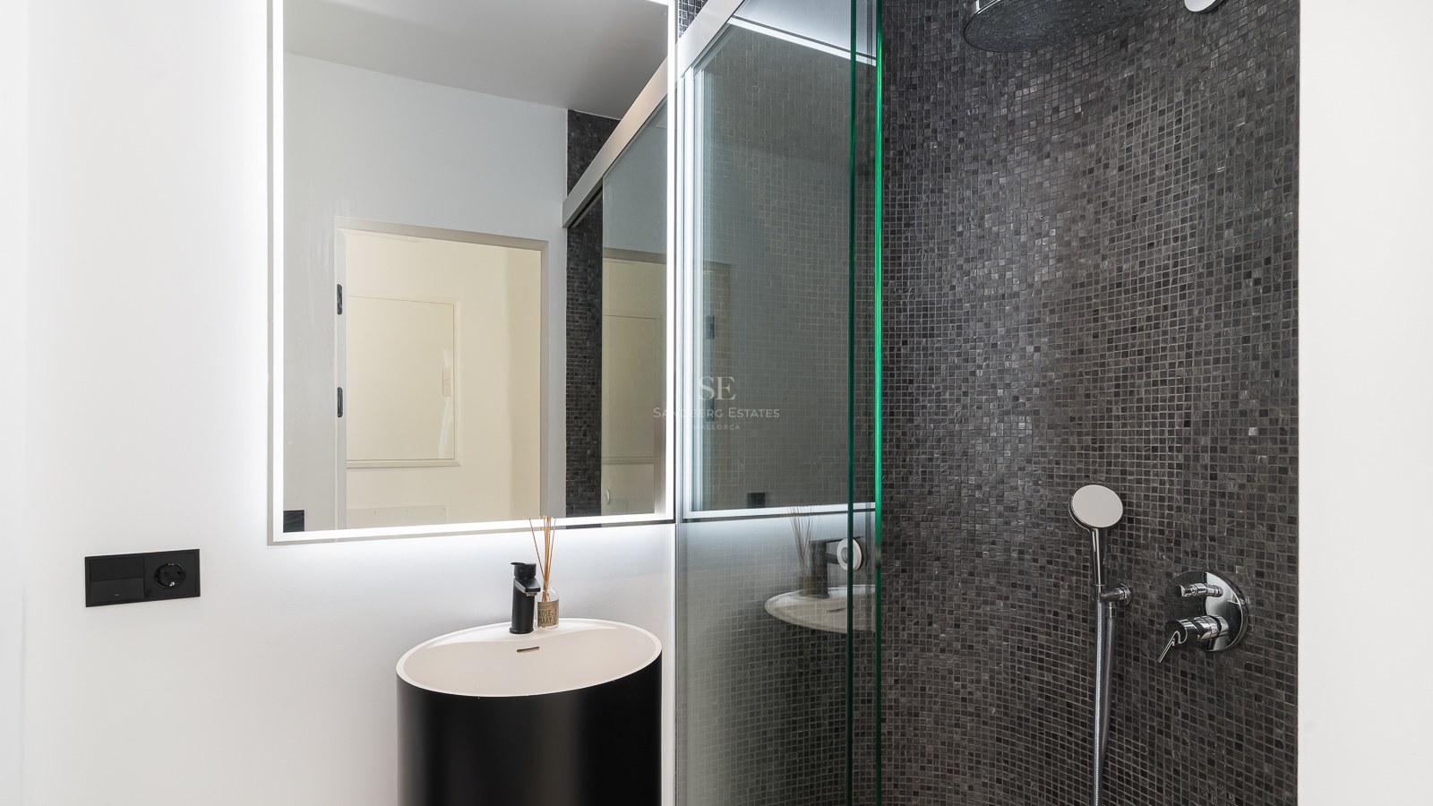 Zeitgenössisches Badezimmer mit schwarzem Design-Waschtisch, LED-Spiegel und begehbarer Mosaik-Dusche in Anthrazit.