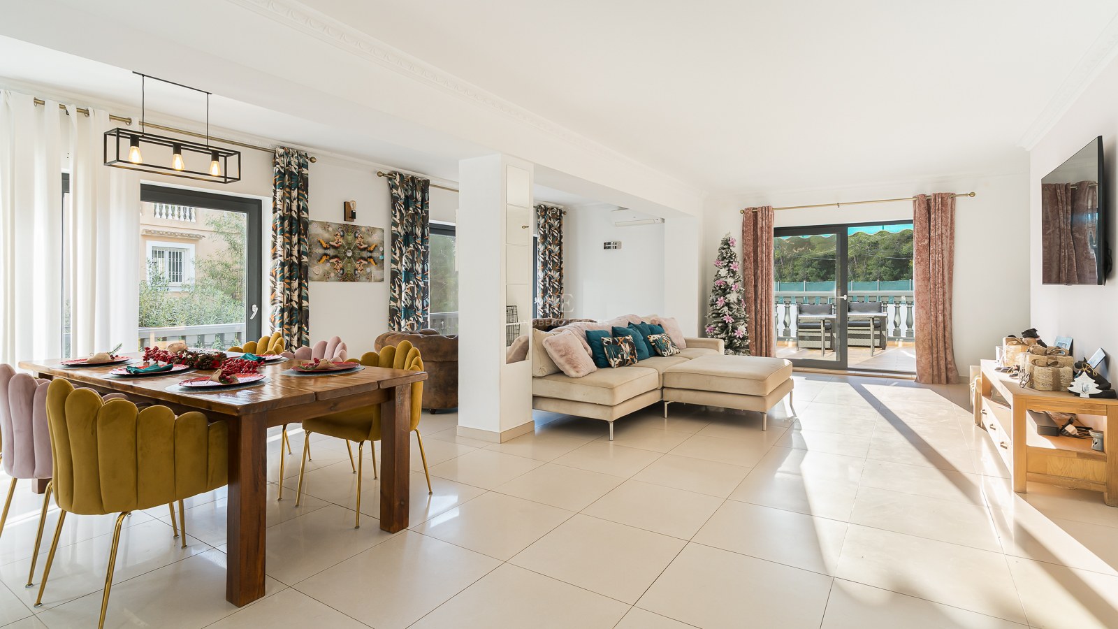 Bright living and dining room featuring mustard velvet chairs, a beige sofa, and large sliding doors to a terrace.