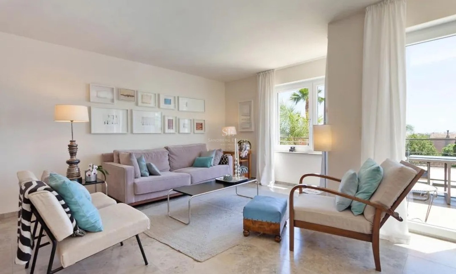 Bright living room with marble floors, mauve sofa, blue accents, and glass doors leading to a sunny terrace with palms.