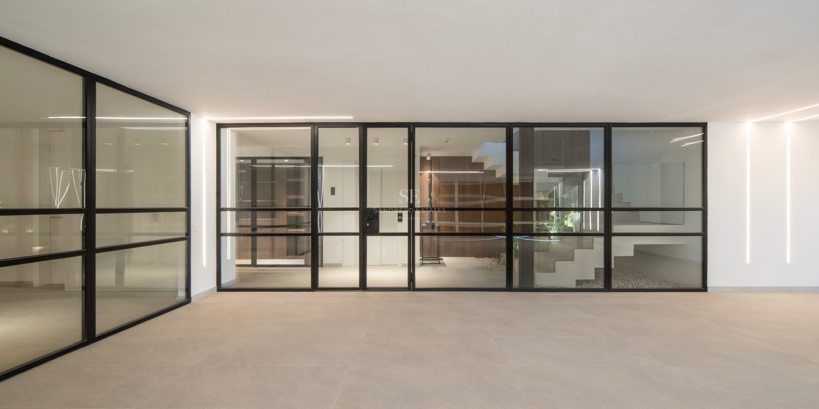 Entrée moderne avec parois vitrées à cadres noirs, carrelage beige et bandes lumineuses LED verticales.