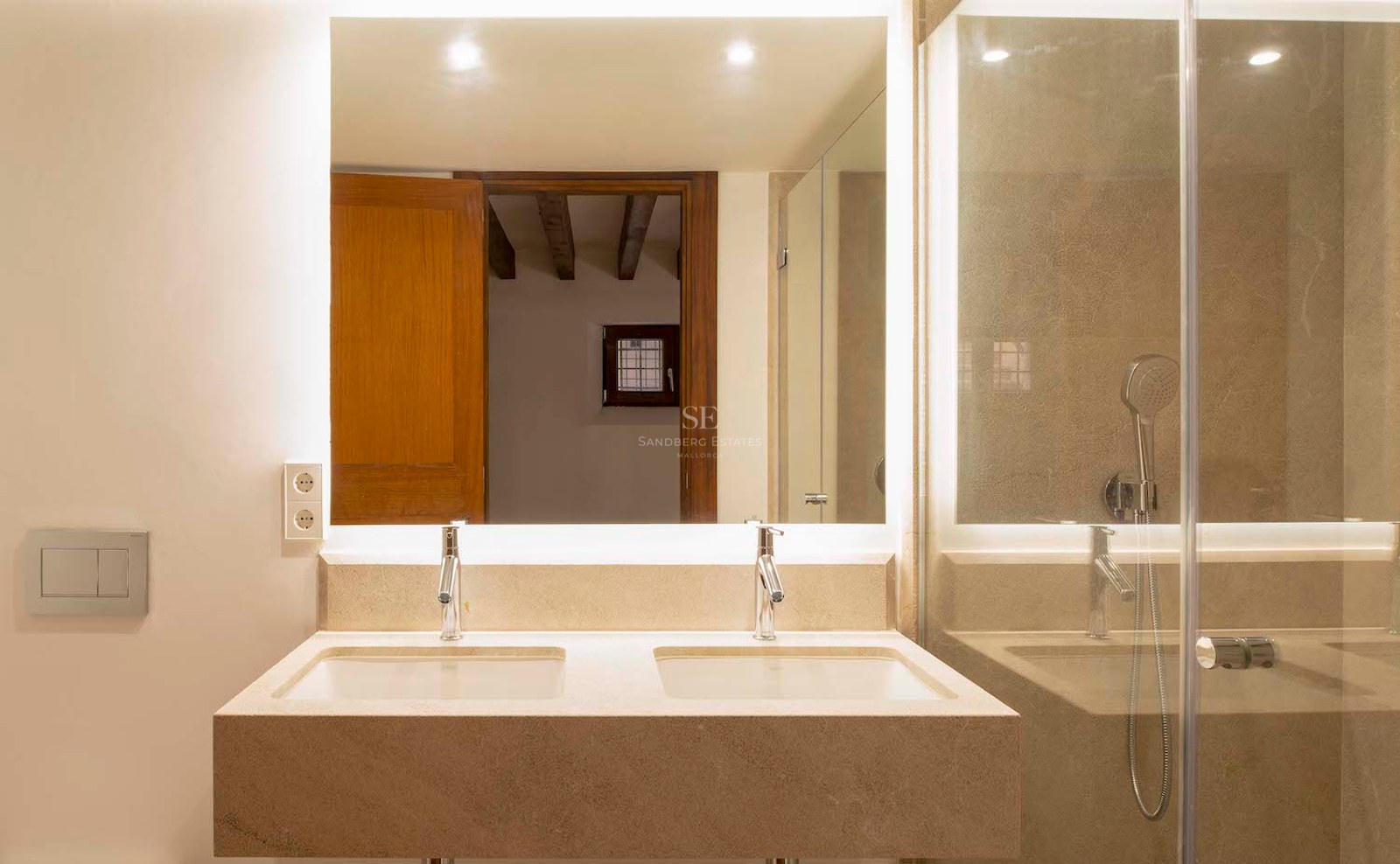 Bathroom with double stone sink, large backlit mirror, and glass shower enclosure.