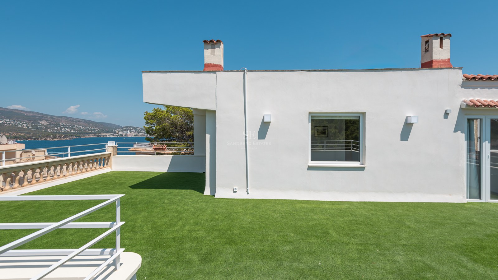 Grande terrasse blanche sur le toit avec gazon synthétique offrant une vue sur la mer Méditerranée.