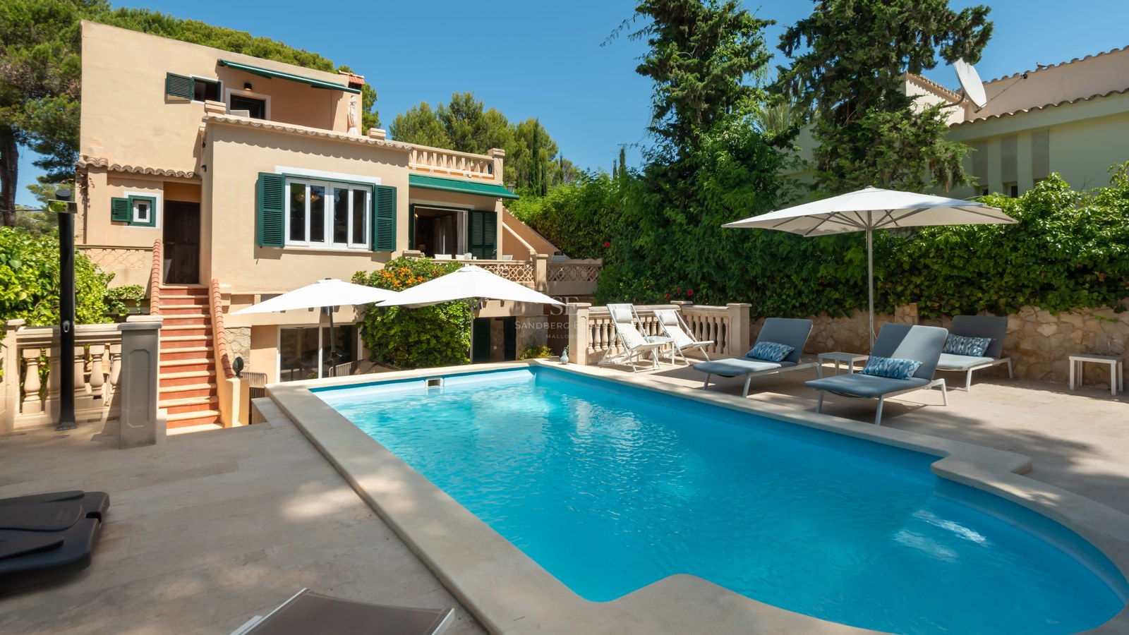 Piscine privée aux eaux turquoises entourée d'une terrasse en pierre et d'une villa méditerranéenne ocre.