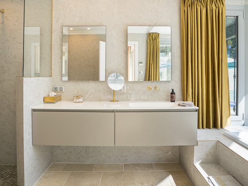 Salle de bains moderne avec meuble double beige, deux miroirs rectangulaires et rideaux dorés.