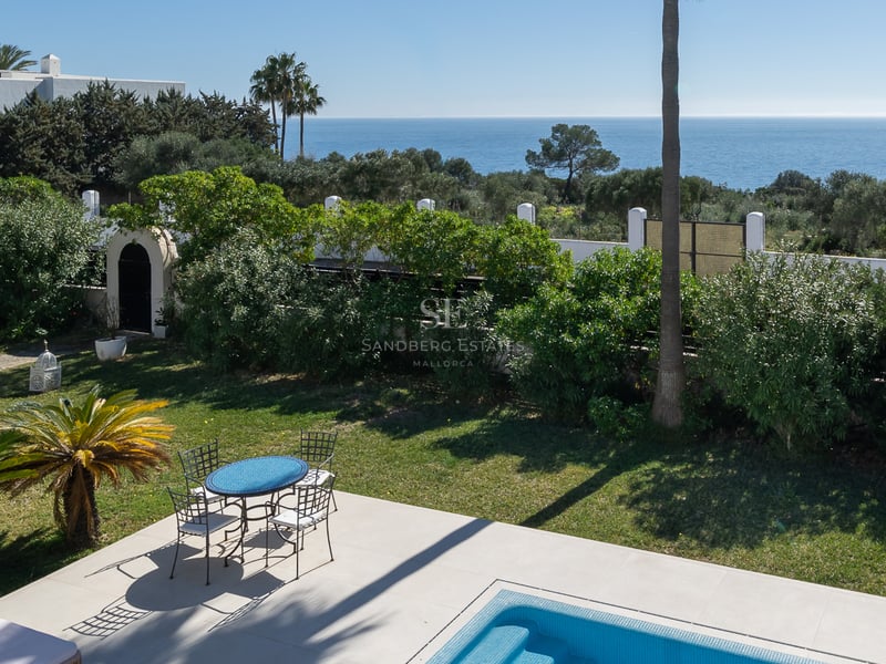 Piscine bleue étincelante et mobilier de jardin surplombant un jardin luxuriant et la mer Méditerranée.