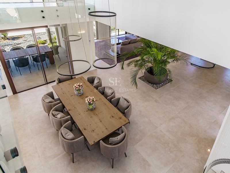 Vue plongeante d'une salle à manger avec table en bois, chaises grises et luminaires suspendus modernes.