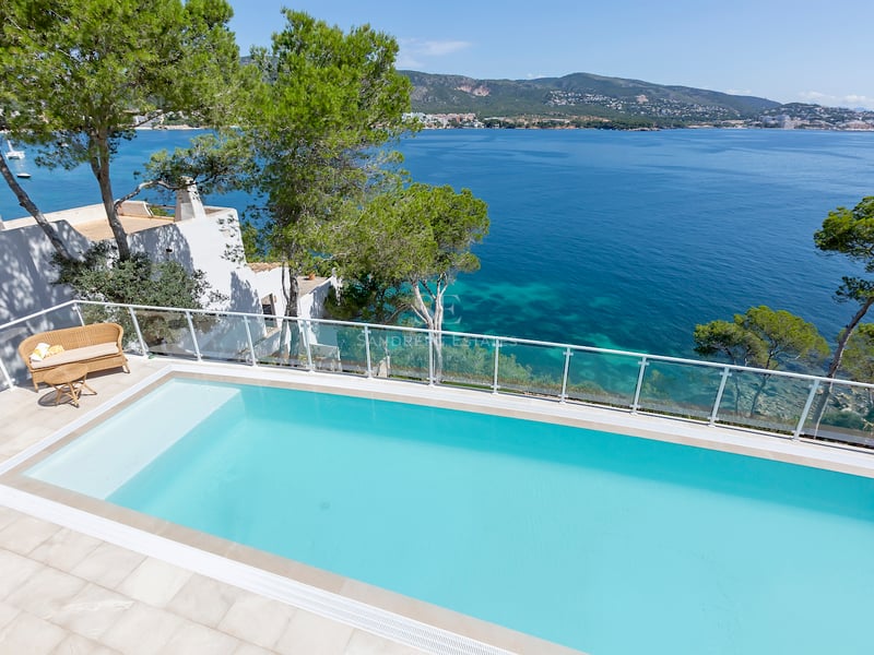 Piscine de luxe avec garde-corps en verre surplombant la mer Méditerranée et le littoral par temps clair.
