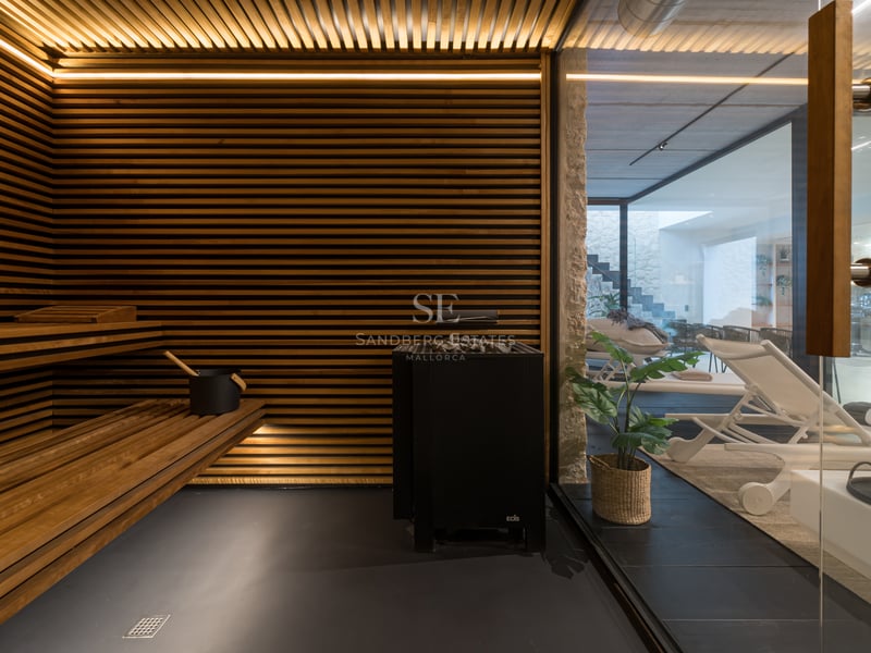 Intérieur d'un sauna de luxe avec lattes de bois horizontales, éclairage LED intégré et vue sur l'espace détente.