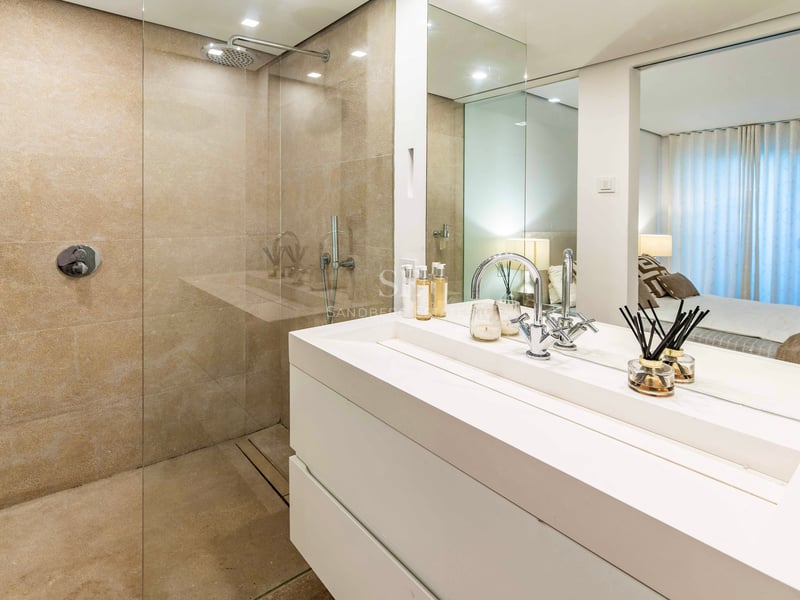 Salle de bains contemporaine avec douche en pierre naturelle, paroi en verre et grand meuble vasque blanc.