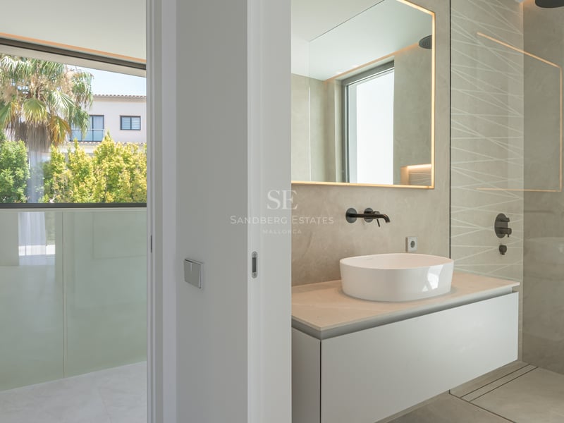 Salle de bains moderne avec vasque à poser, robinetterie noir mat et douche à l'italienne à côté d'une fenêtre vue jardin.
