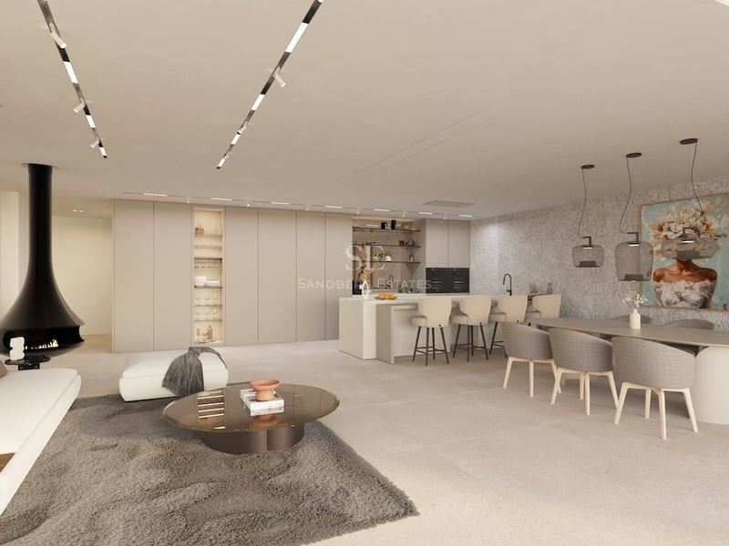Espace de vie ouvert spacieux avec canapé blanc, cheminée noire design, salle à manger et cuisine aux tons neutres.