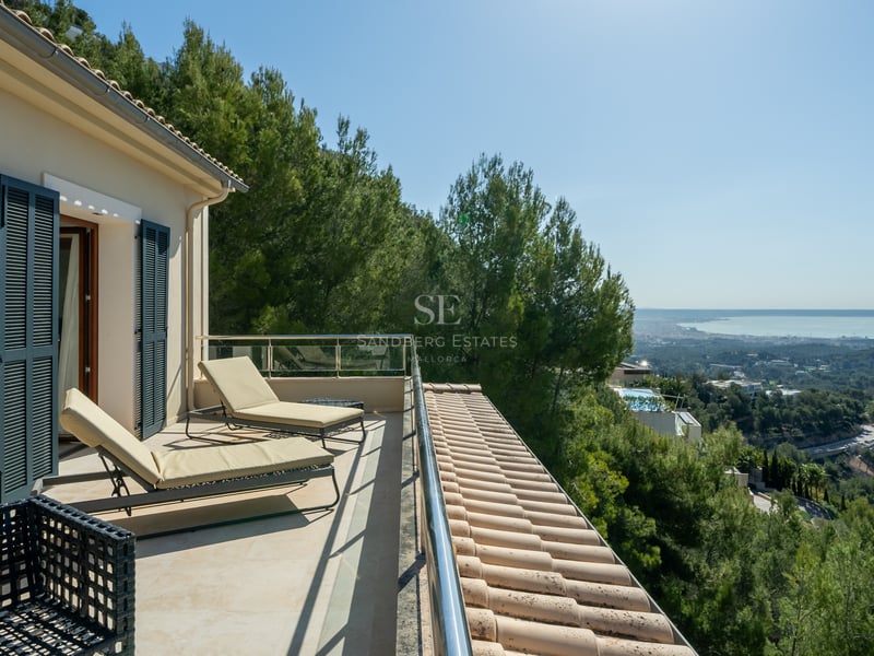 Terrasse de luxe avec bains de soleil, garde-corps en verre et vue imprenable sur la vallée et la mer.