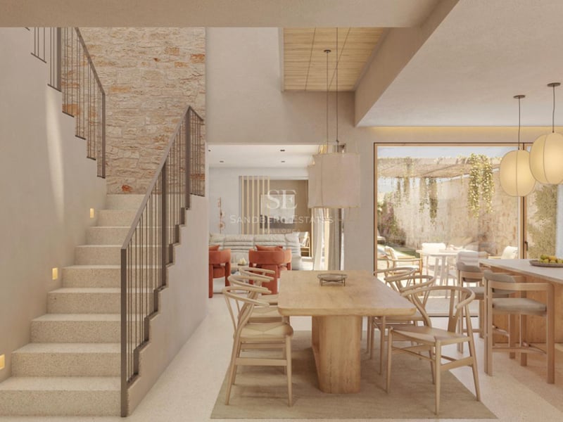 Intérieur moderne lumineux avec une grande table en bois, un mur en pierre et un élégant escalier en pierre.