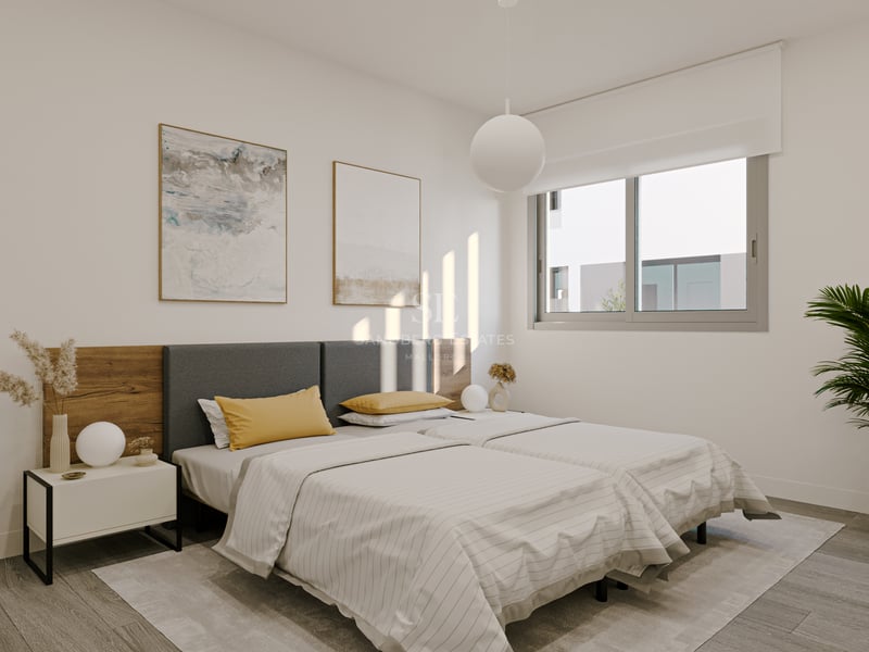 Dormitorio luminoso con camas individuales, cabecero de madera y tela, mesita minimalista y ventana al exterior.