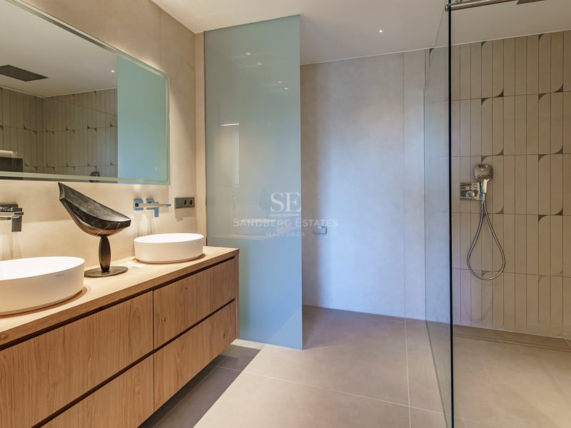 Salle de bains contemporaine avec meuble en bois clair, vasques à poser et grande douche à l'italienne.