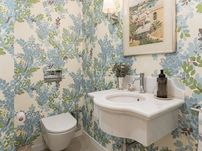 Toilettes invités avec papier peint floral, vasque en marbre sculpté et WC suspendu.
