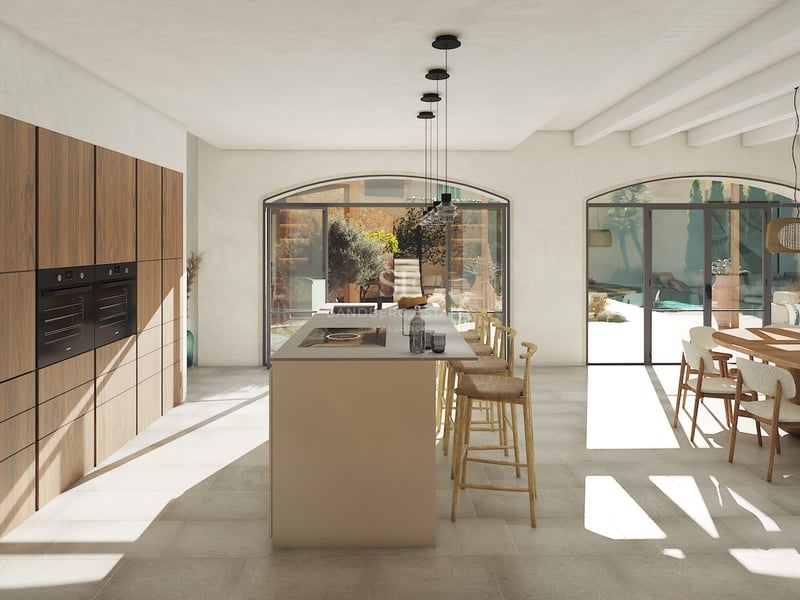 Cocina moderna de planta abierta con gran isla central, armarios de nogal y puertas de cristal en arco hacia el patio.