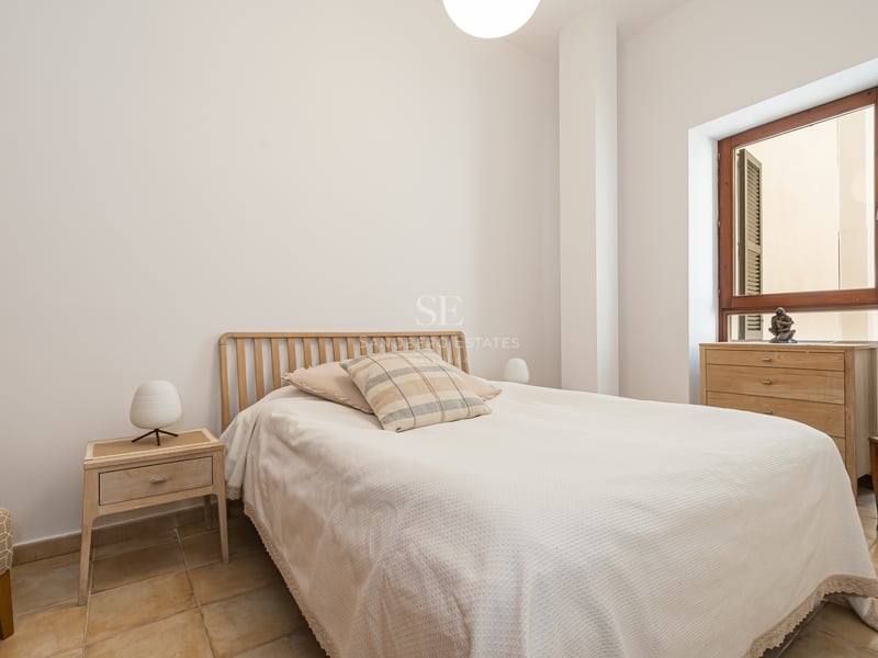 Chambre minimaliste avec sol en terre cuite, meubles en bois clair et fenêtre à cadre en bois naturel.