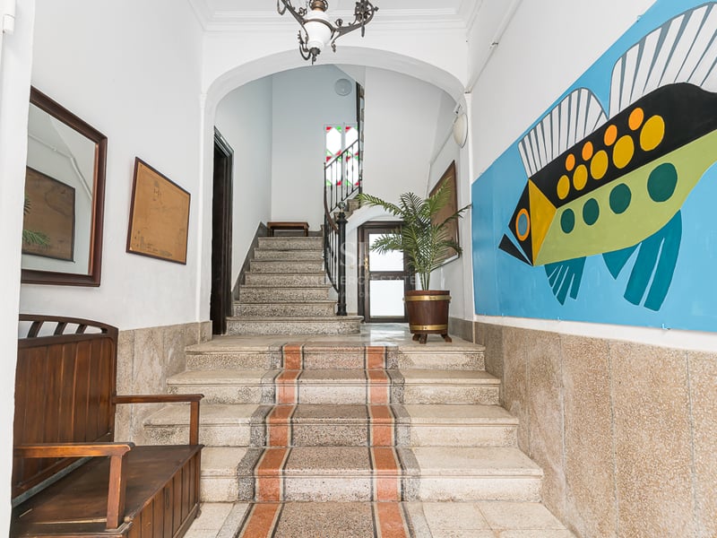 Entrée avec escalier en pierre, banc en bois et une grande fresque de poisson coloré sur le mur.